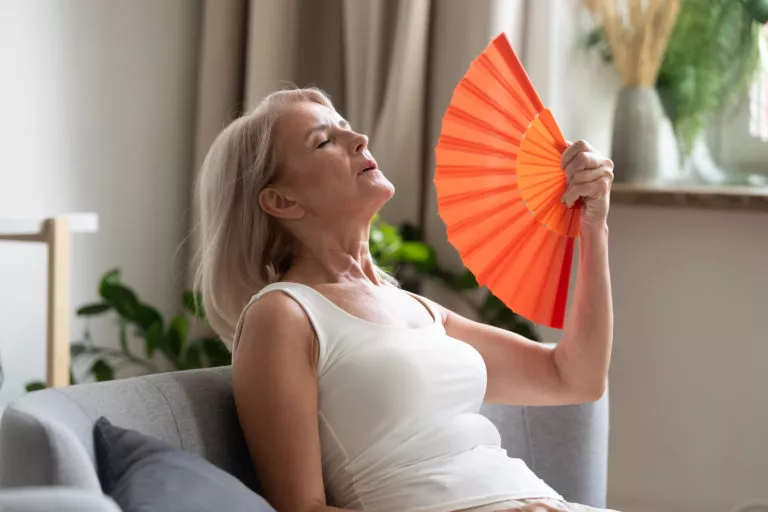 Woman sitting on couch and fanning herself